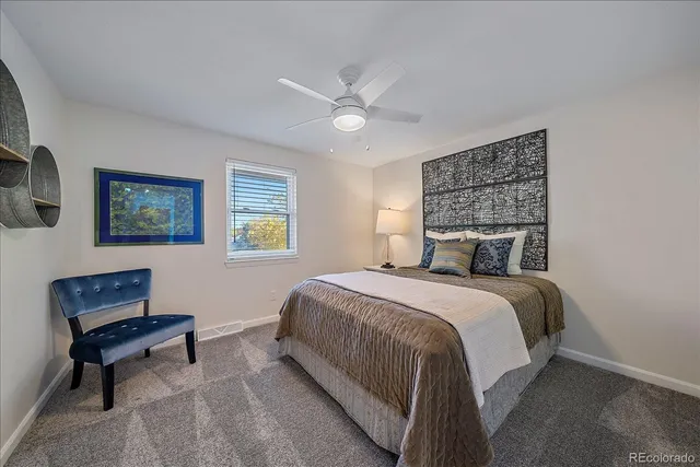 a bedroom with a bed a chair and painting on the wall