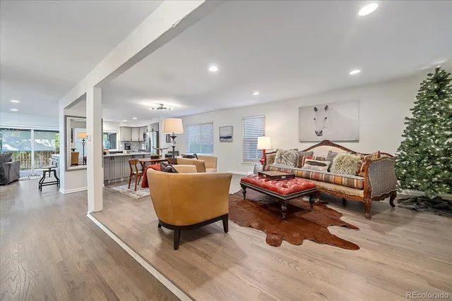 a living room with furniture a wooden floor and a kitchen view