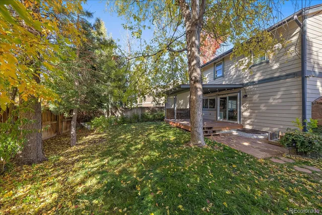 a backyard of a house with plants and large tree