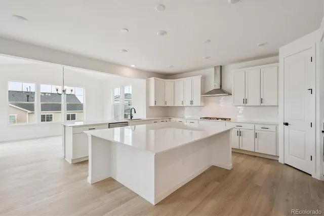 a large white kitchen with stainless steel appliances granite countertop a lot of counter space and wooden floors