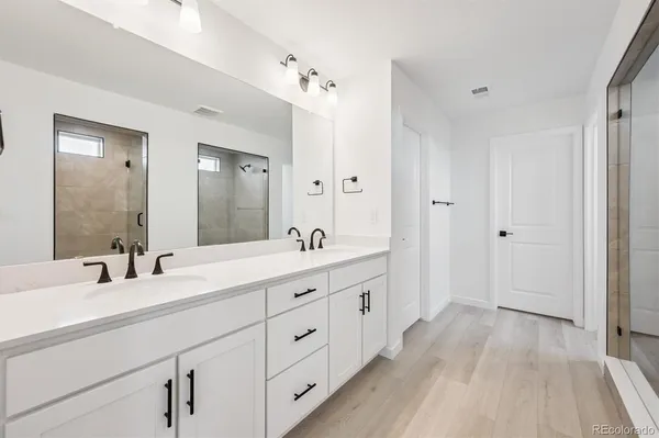 a spacious bathroom with a double vanity sink a mirror and a shower