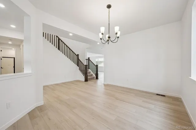 a view of an empty room with wooden floor and staircase