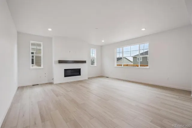 an empty room with windows and fireplace
