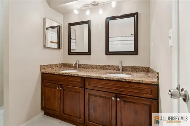 a bathroom with a granite countertop double vanity sink and mirror