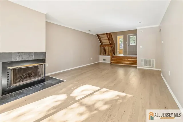 an empty room with wooden floor fireplace and windows