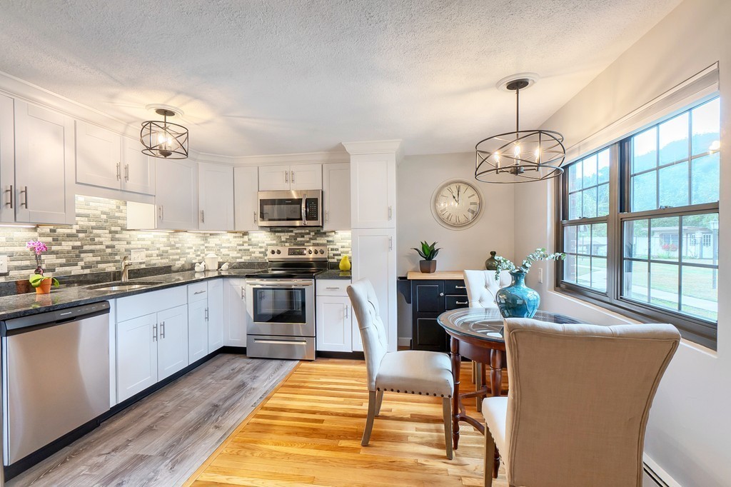 84 Renwick Road, Unit C Wakefield, MA 01880 - Photo 9 of 29 a kitchen with stainless steel appliances granite countertop a stove a sink dishwasher a dining table and chairs with wooden floor