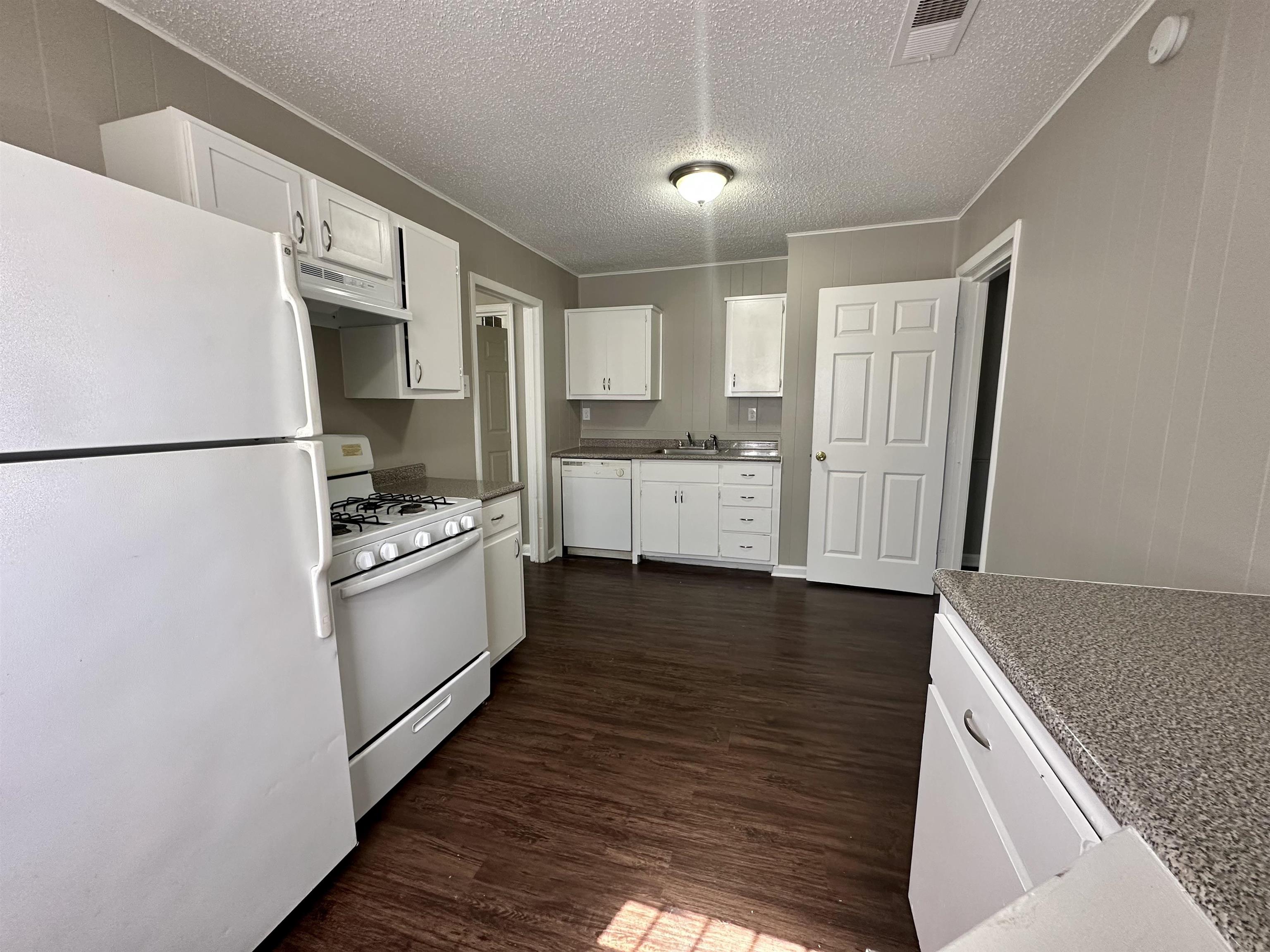 296 Glencoe Road Memphis, TN 38109 - Photo 13 of 18 a kitchen with granite countertop a refrigerator a sink and white cabinets