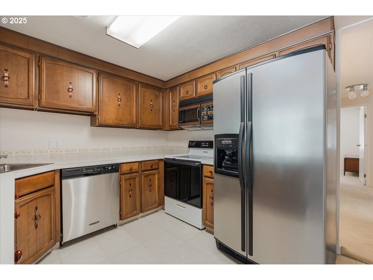 790 Southeast Webber Street, Unit 305 Portland, OR 97202 - Photo 16 of 30 a kitchen with stainless steel appliances granite countertop a refrigerator and a stove top oven