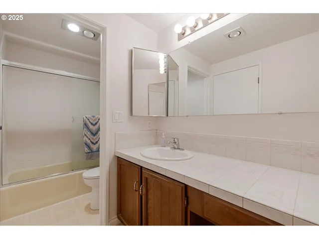 a bathroom with a sink vanity granite tub shower and a mirror