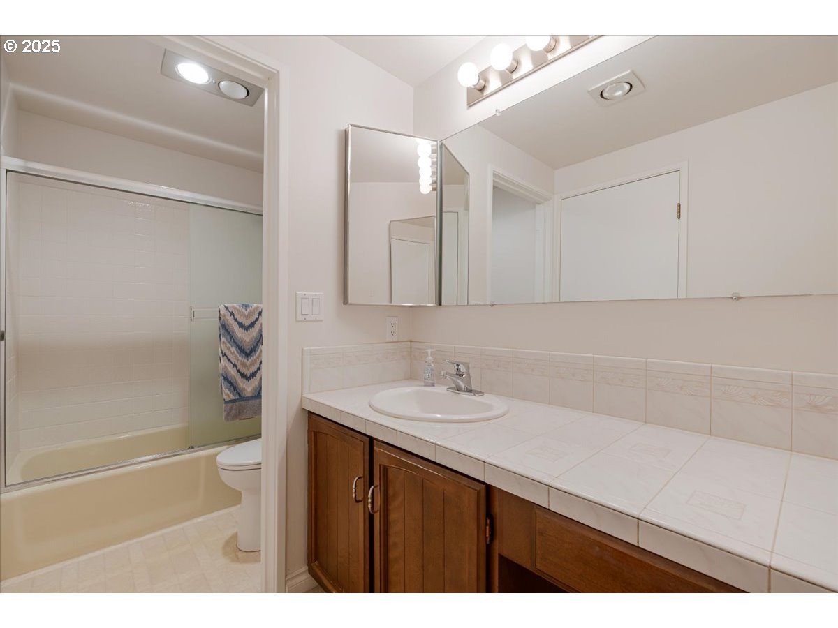 790 Southeast Webber Street, Unit 305 Portland, OR 97202 - Photo 20 of 30 a bathroom with a sink vanity granite tub shower and a mirror