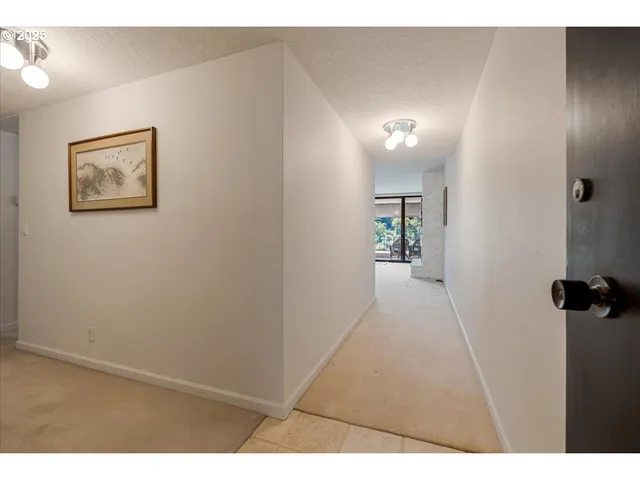 a view of a hallway with wooden floor and a bathroom