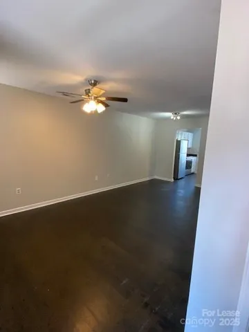 an empty room with wooden floor and fan