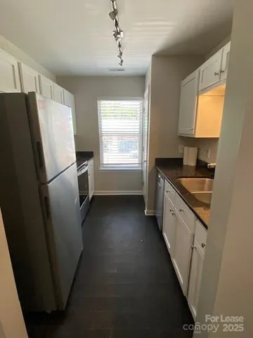 a kitchen with granite countertop a refrigerator a sink a stove and island