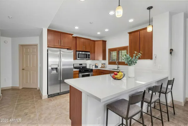 a kitchen with stainless steel appliances granite countertop a sink a stove a refrigerator cabinets and a dining table