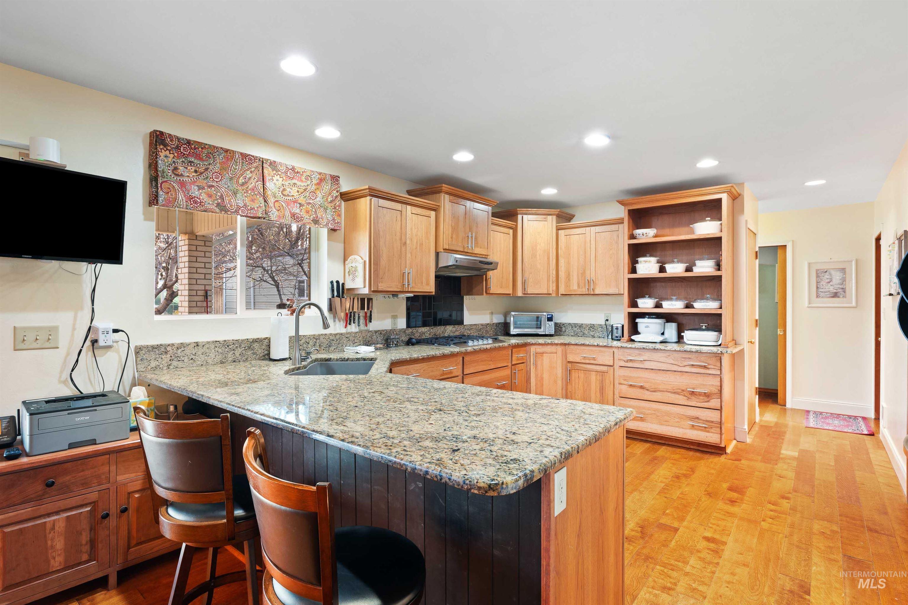 430 Pierce Street Twin Falls, ID 83301 - Photo 8 of 39 Kitchen with a peninsula, light stone countertops, a breakfast bar area, light wood-style floors, and open shelves