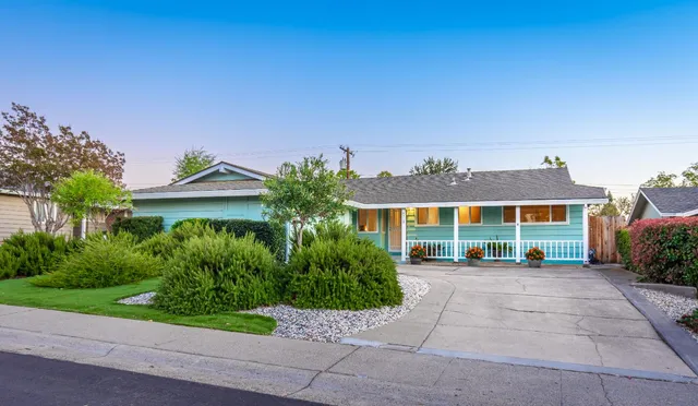 a front view of a house with a yard and potted plants