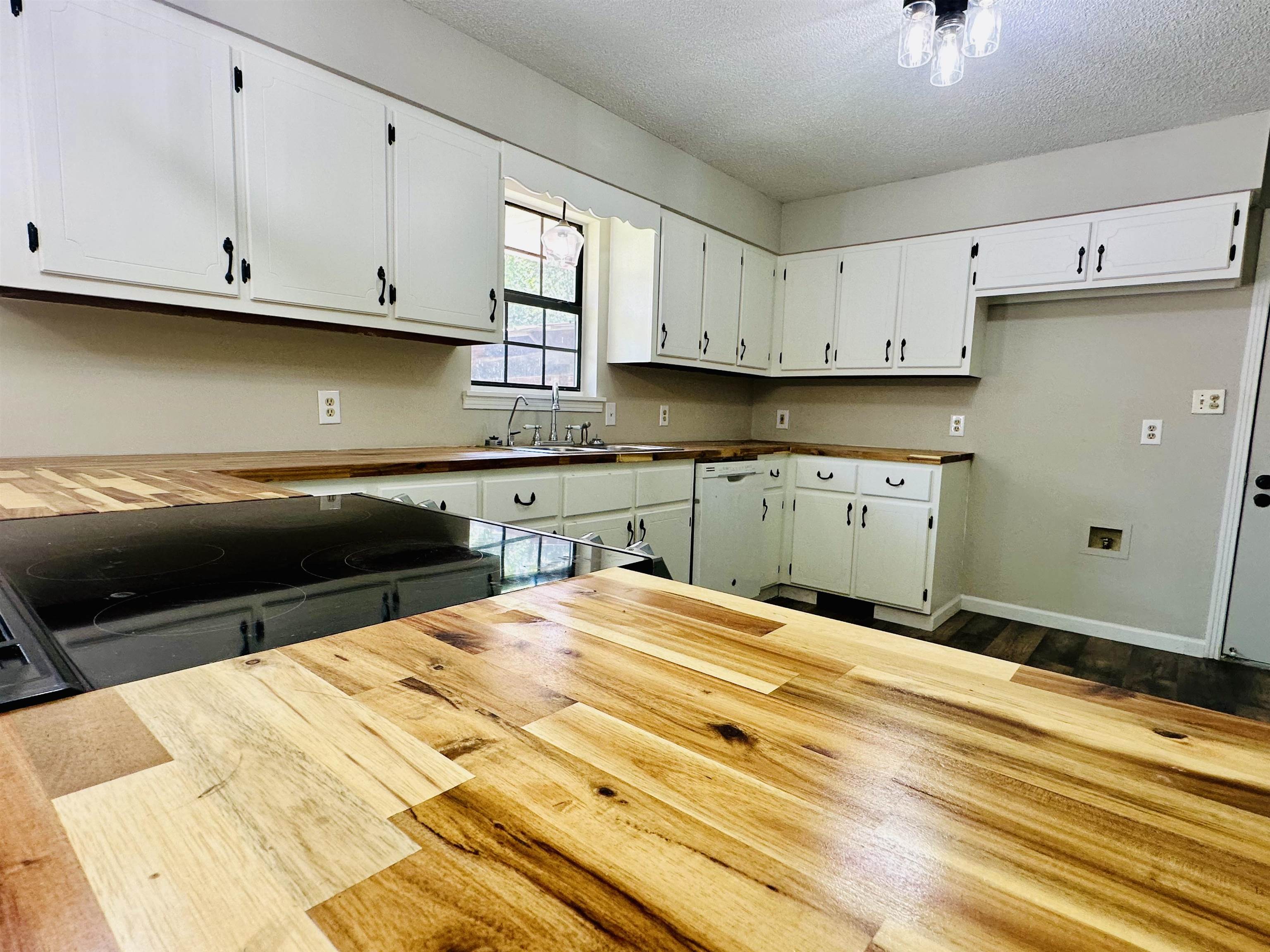 287 Gilchrist Stantonville Road Adamsville, TN 38310 - Photo 10 of 29 Kitchen featuring a textured ceiling, white cabinets, dishwasher, dark wood finished floors, and wooden counters