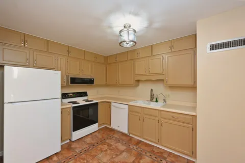 a kitchen with stainless steel appliances granite countertop a sink a stove a refrigerator a white stove top oven and white cabinets