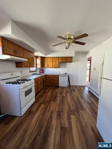 a kitchen with stainless steel appliances a stove a sink and white cabinets with wooden floor