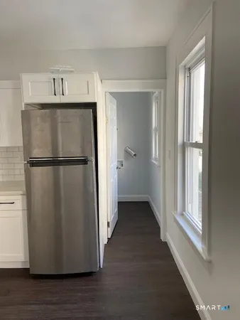 a view of a refrigerator in kitchen and an empty room