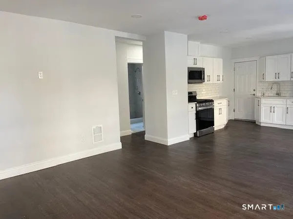 a view of cabinets stainless steel appliances wooden floor and window
