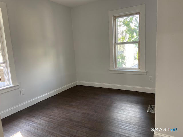 666 Capitol Avenue, Unit 2 Bridgeport, CT 06606 - Photo 10 of 14 an empty room with wooden floor and windows