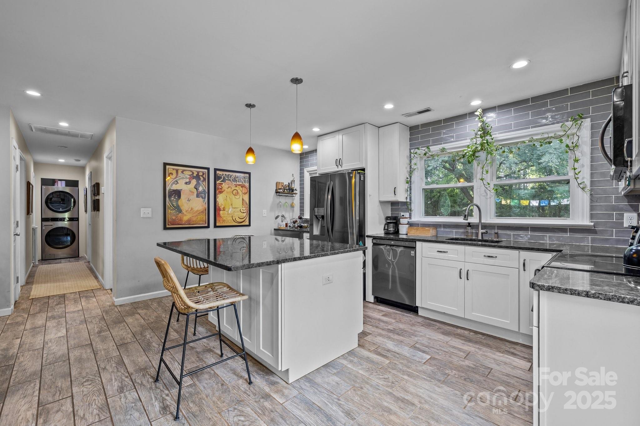 a kitchen with stainless steel appliances granite countertop a stove top oven a sink a refrigerator and white cabinets with wooden floor