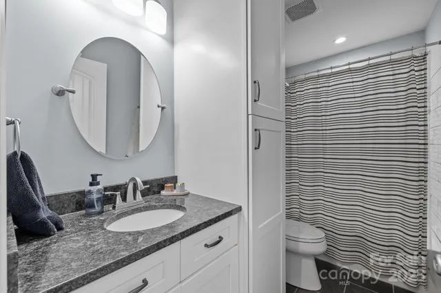 a bathroom with a granite countertop toilet sink and mirror