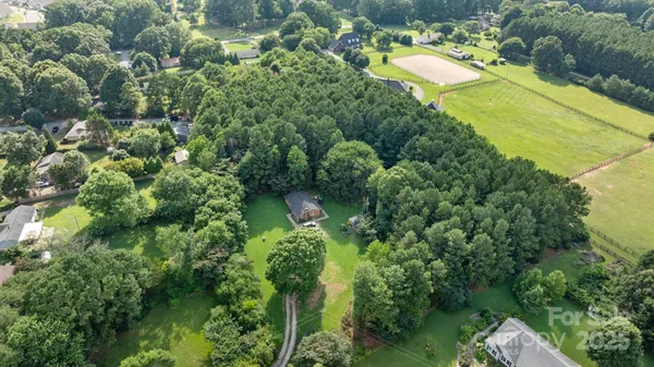 an aerial view of residential house with outdoor space and trees all around