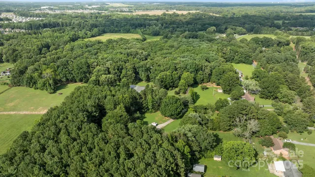 an aerial view of residential houses with outdoor space and trees