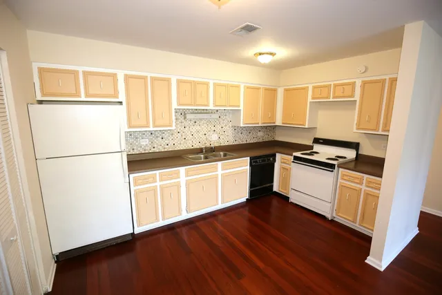 a kitchen with granite countertop a refrigerator a sink dishwasher and a stove with wooden floor