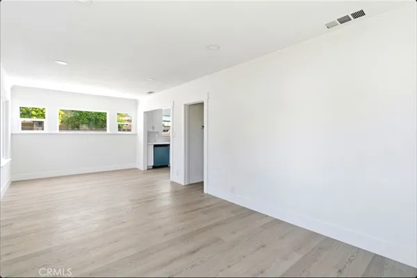 a view of a big room with wooden floor and windows