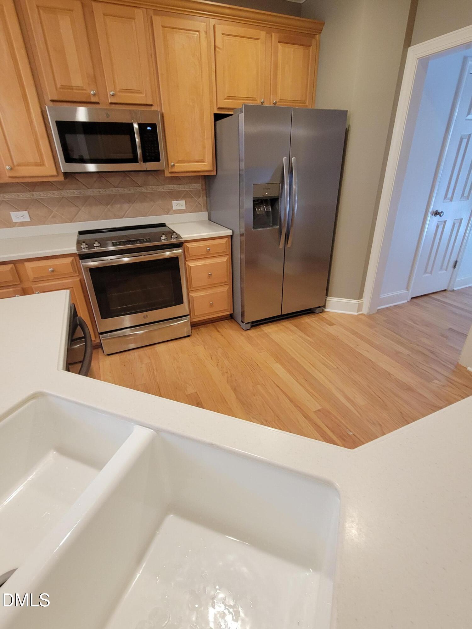 4044 Barton Park Place Raleigh, NC 27613 - Photo 11 of 20 a kitchen with wooden cabinets and stainless steel appliances