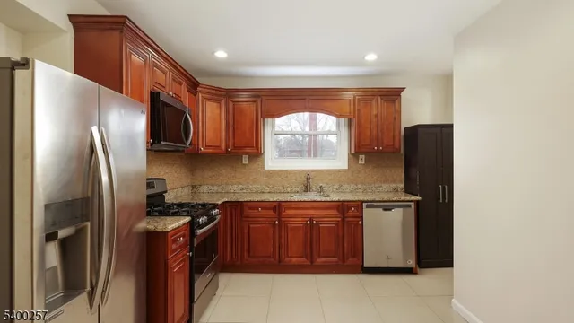 a kitchen with stainless steel appliances granite countertop a refrigerator a sink a stove and island