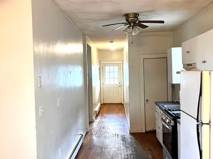 a view of a kitchen with a refrigerator a sink wooden floor a ceiling fan