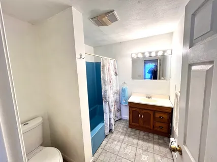 a bathroom with a granite countertop sink mirror vanity and toilet