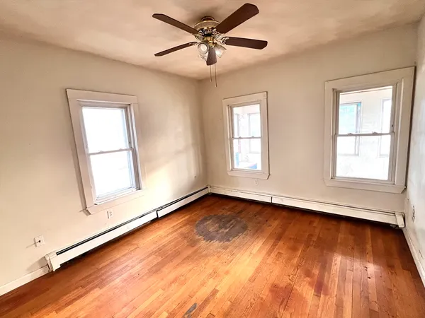 a view of an empty room with window and wooden floor