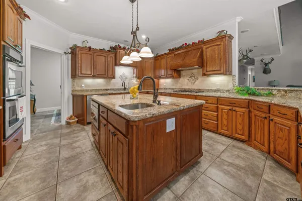 a kitchen with kitchen island granite countertop a sink stove and cabinets