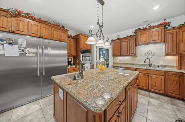 a kitchen with stainless steel appliances granite countertop a sink refrigerator and cabinets