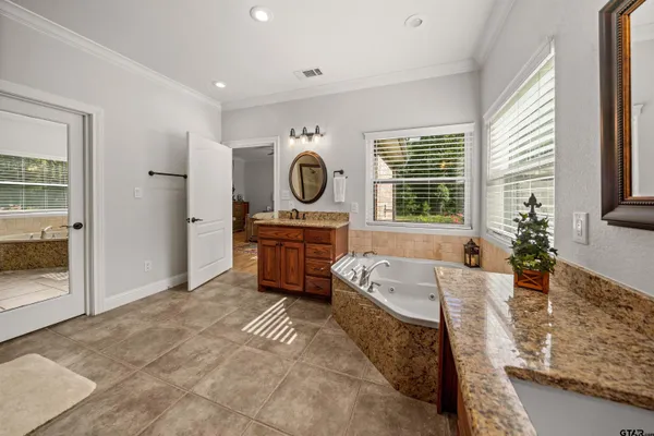 a spacious bathroom with a tub a sink and a large mirror