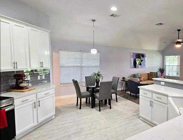 a kitchen with cabinets table and chairs