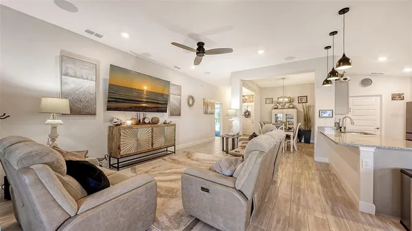 a living room with furniture a flat screen tv and kitchen view
