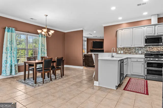 a open kitchen with stainless steel appliances granite countertop a stove top oven a sink a dining table and chairs with the view of living room