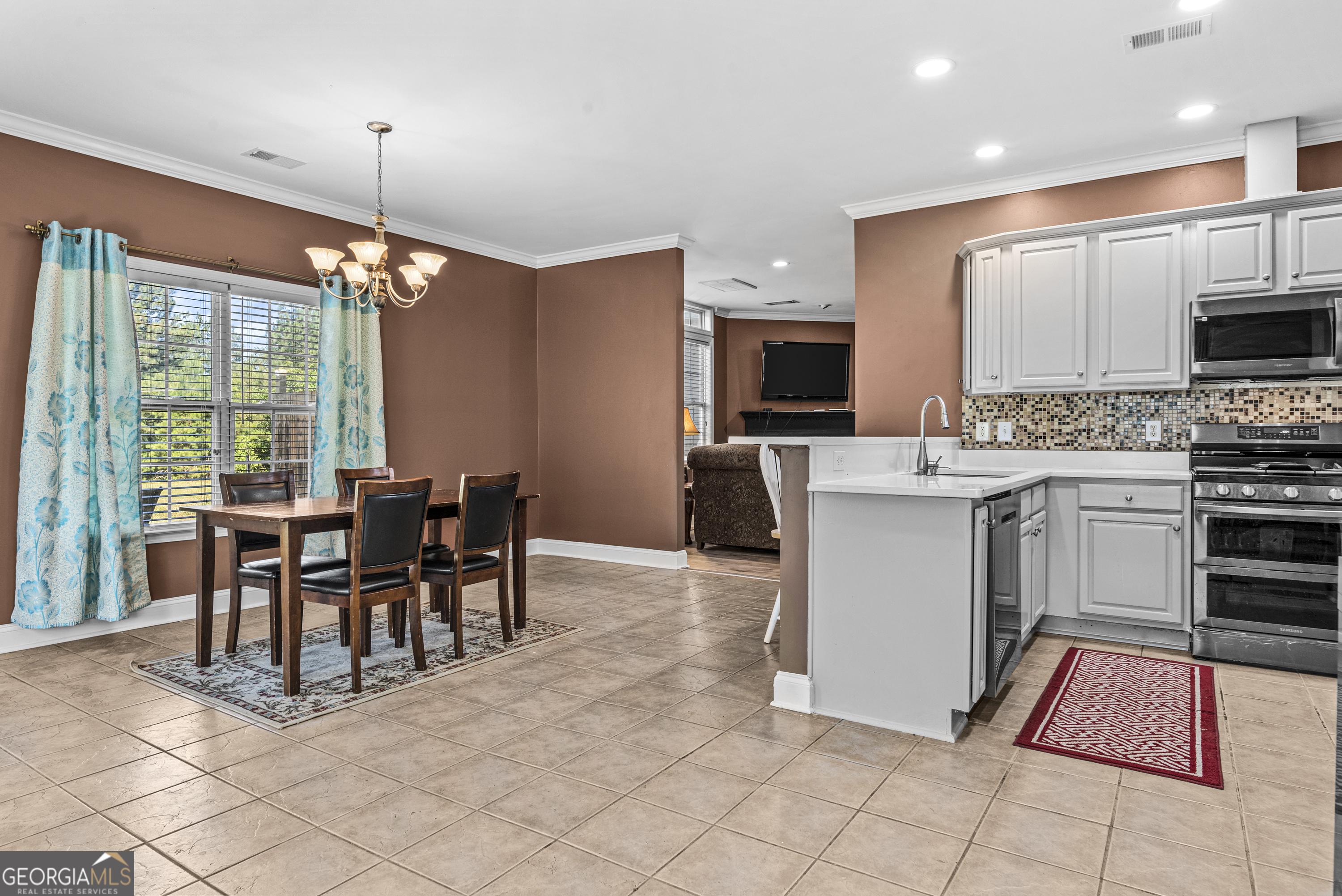 1141 Whispering Lakes Trail Madison, GA 30650 - Photo 12 of 40 a open kitchen with stainless steel appliances granite countertop a stove top oven a sink a dining table and chairs with the view of living room