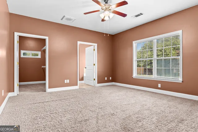 an empty room with a ceiling fan and window
