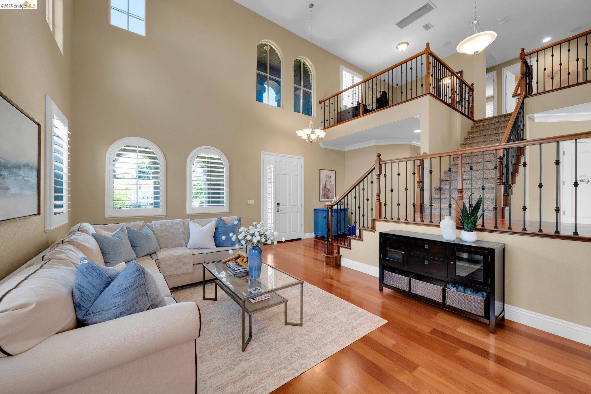 2513 Winged Foot Road Brentwood, CA 94513 - Photo 3 of 45 Two-story living area with high ceilings, multiple arched windows with white plantation shutters, and polished wood-finish flooring