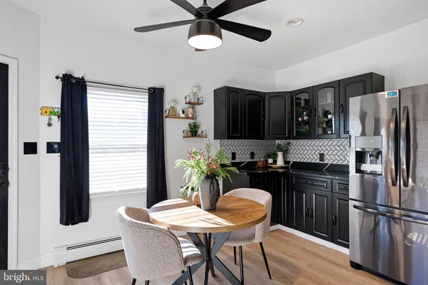 a kitchen with stainless steel appliances granite countertop a refrigerator a stove a sink a dining table and chairs with wooden floor