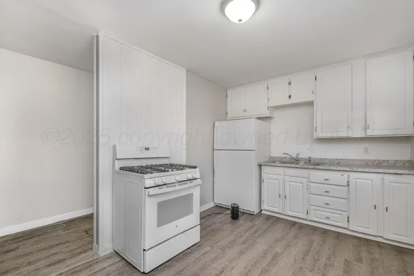 a kitchen with granite countertop white cabinets and white appliances
