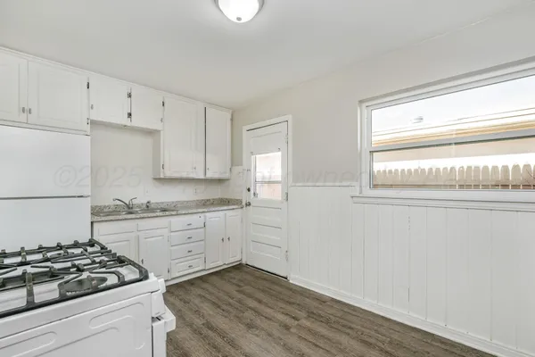 a kitchen with granite countertop white cabinets and white appliances