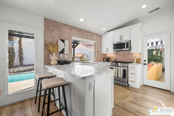 a kitchen with stainless steel appliances granite countertop a stove a sink and a microwave